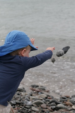 Spaß beim Steinewerfen an der Ostsee Foto: Kind wirft Steine ins Wasser